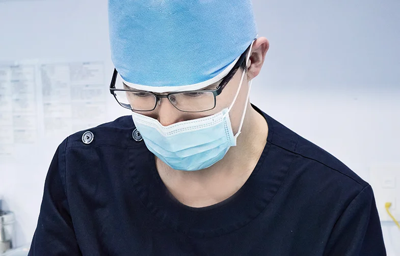 Medical professional in a surgical cap, glasses and mask